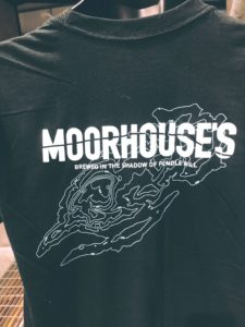 A close up back shot of Moorhouse's Black Short Sleeve T-Shirt with Moorhouse's logo large across the back and a graphic outline of Pendle Hill.